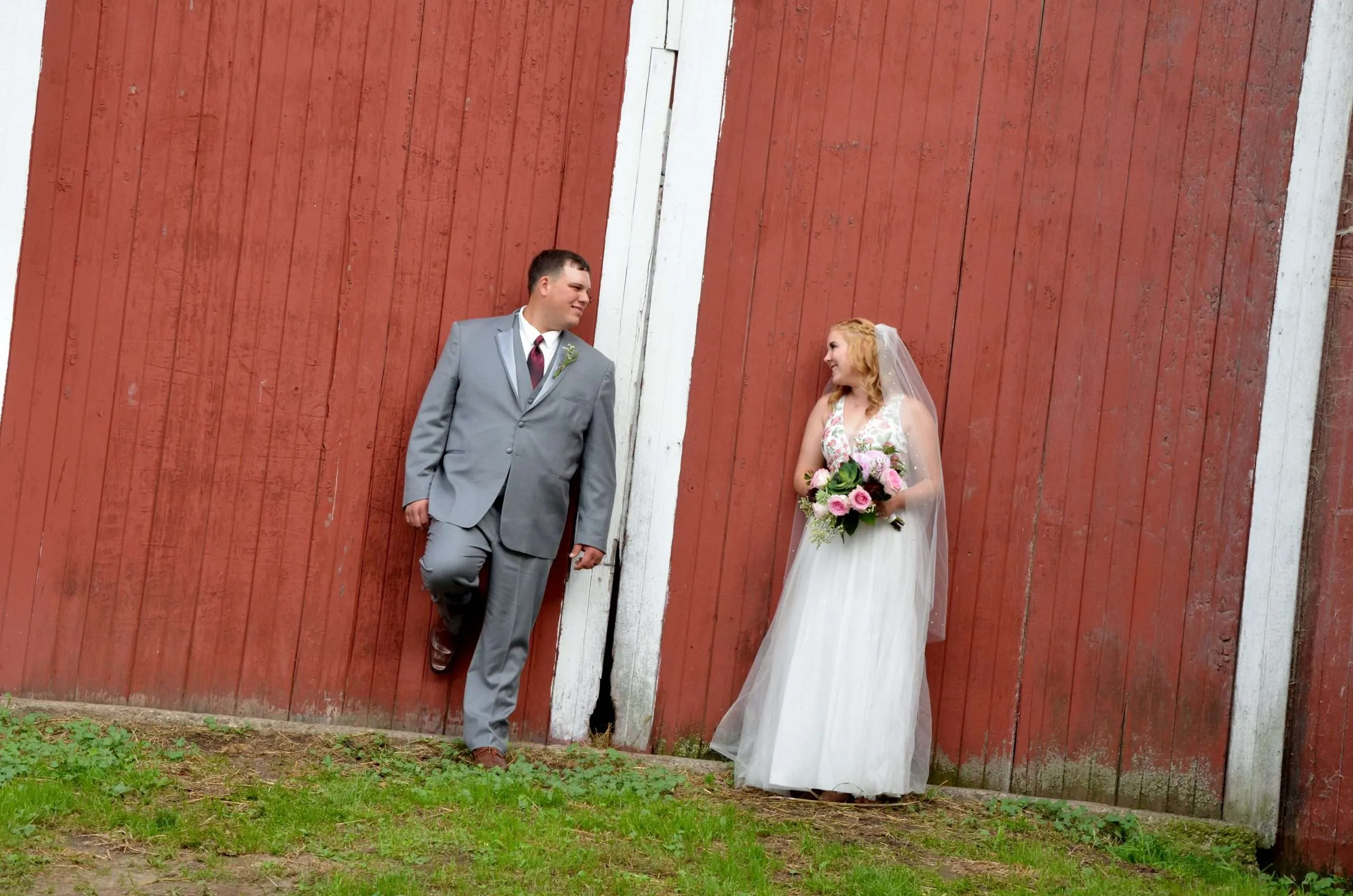 Bride and groom in front of a red barn